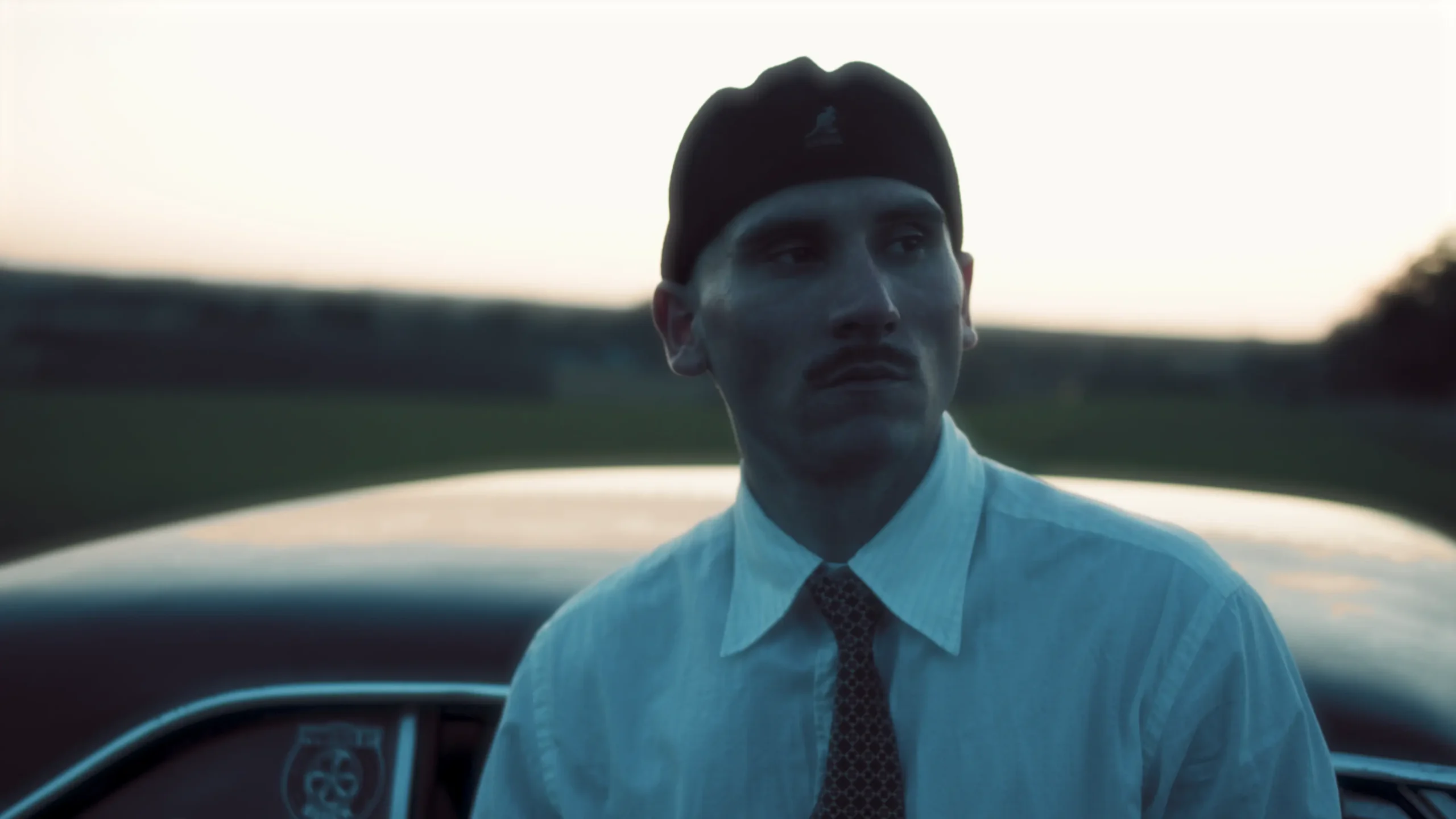 OKAYNICO står foran bil og kigger ud i horisonten